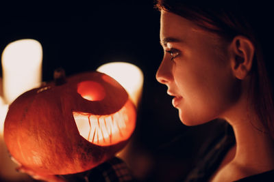 Young woman holding pumpkin in dark