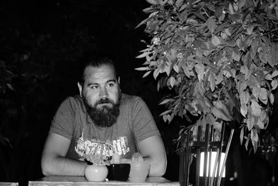 Bearded man sitting at table in restaurant during night