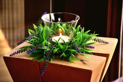 High angle view of lit candle in container by flowers on table