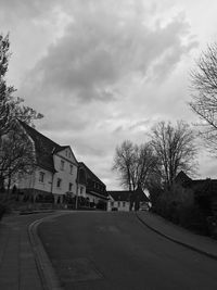 Houses by road against sky in city