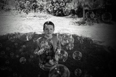 Portrait of boy playing with bubbles at public park