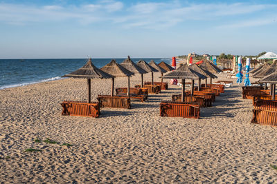 Deck chairs on beach against sky