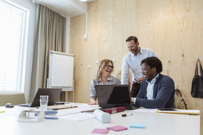 Cheerful business colleagues sitting at conference table in board room