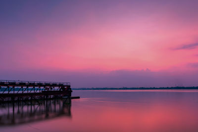 Pier over lake against romantic sky at sunset