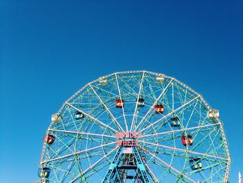 Low angle view of ferris wheel against blue sky