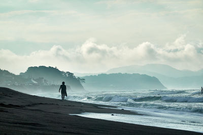 Silhouette person standing on beach against sky