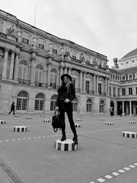 Full length portrait of woman wearing sunglasses against sky in city
