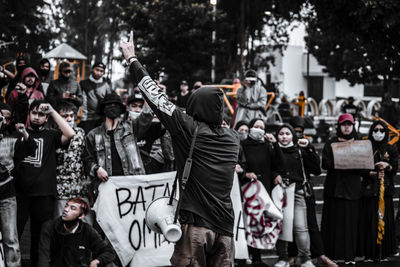 Rear view of people standing on street in city