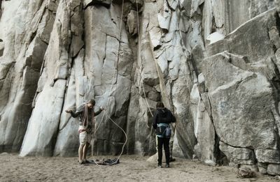 People wearing safety harness against rock formation