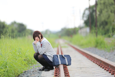 Portrait of woman sitting railroad track