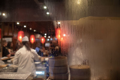 People seen through glass window in restaurant at night 