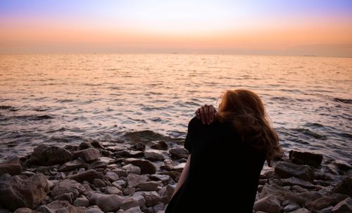 Rear view of woman standing on beach against clear sky