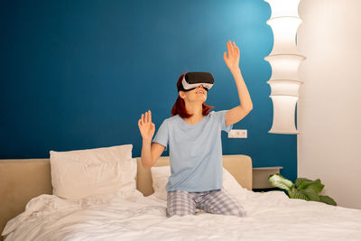 Portrait of young woman standing on bed at home