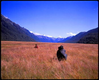 Rear view of people on field against sky