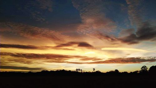 Silhouette landscape against dramatic sky during sunset