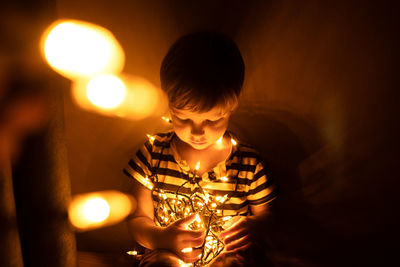 Full length of boy with illuminated lights at home