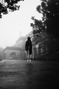 Woman levitating on road leading towards church in foggy weather