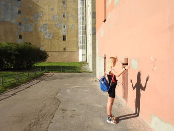 Side view full length of girl standing outside building on sunny day