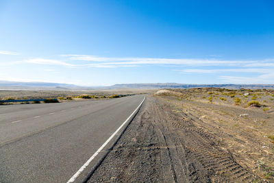 Road leading towards landscape against sky