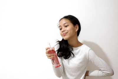 Smiling young woman holding drink against white background