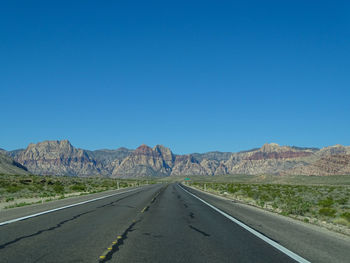 Road by mountains against clear sky