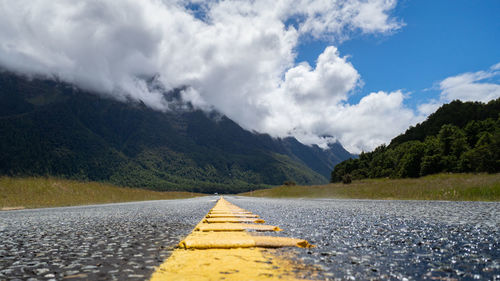 Surface level of road by mountains against sky