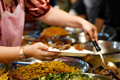 Midsection of people having food in market