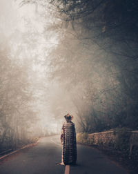 Rear view of person standing on road during foggy weather