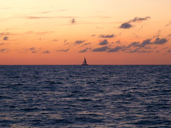 Silhouette of sailboat in sea during sunset