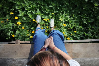 High angle view of female sitting on boardwalk by grassy land