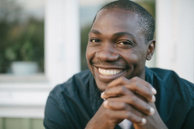 Portrait of smiling mid adult man with hands clasped