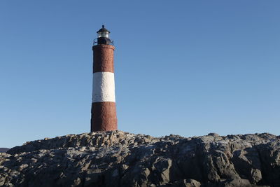 Lighthouse by sea against clear sky