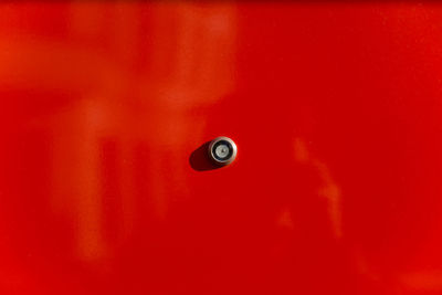 Close-up of peephole on red door