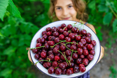 Smiling girl showing bowl of cherries