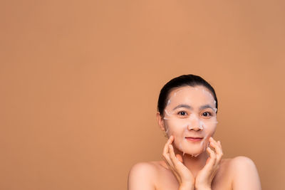 Portrait of young woman against orange background