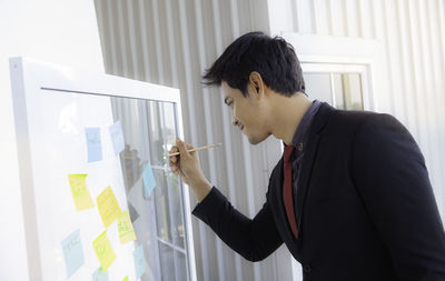 Businessman writing on glass at office