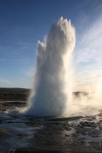 Geyser erupting against sky