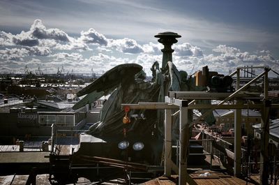 Statue in city against cloudy sky