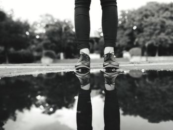Low section of person standing on puddle with reflection