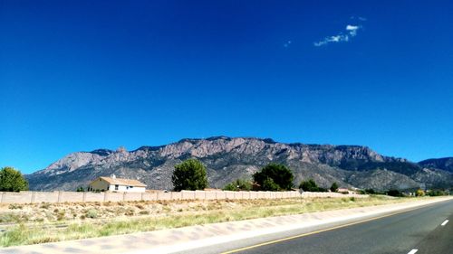 Road by mountains against blue sky