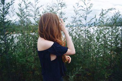 Rear view of young woman standing against plants