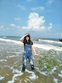 Young woman standing in sea against sky