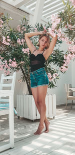 Portrait of young woman standing by flowering plants