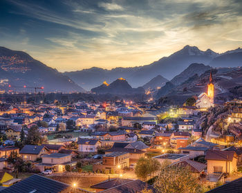 High angle view of illuminated city against sky at sunset