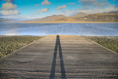 Shadow of person on sea against sky