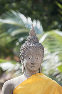 Old buddha statue against trees at wat yai chai mongkhon