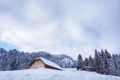 White house on snow field against sky