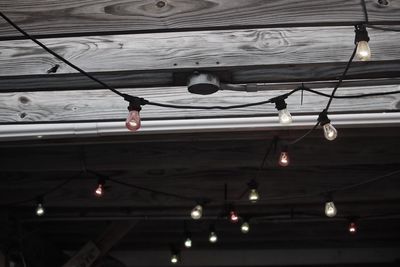 Low angle view of illuminated light bulbs hanging on ceiling