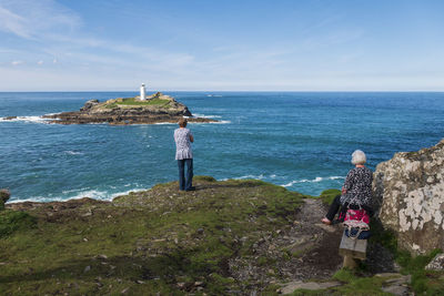 Rear view of man looking at sea against sky