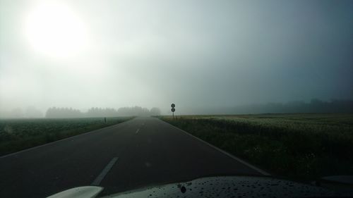 Cropped image of car on road against sky during foggy weather